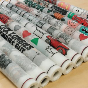 Multiple rolled DTF gang sheets with colourful custom designs ready for garment transfers by DTFPrintWorx UK